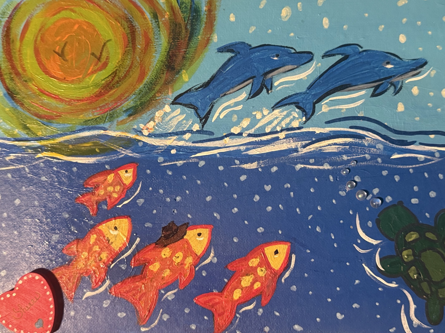 Close-up of dolphins and colorful fish beneath a swirling sun