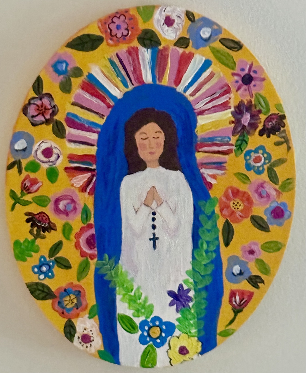 Colorful oval portrait of Our Lady of Guadalupe surrounded by flowers