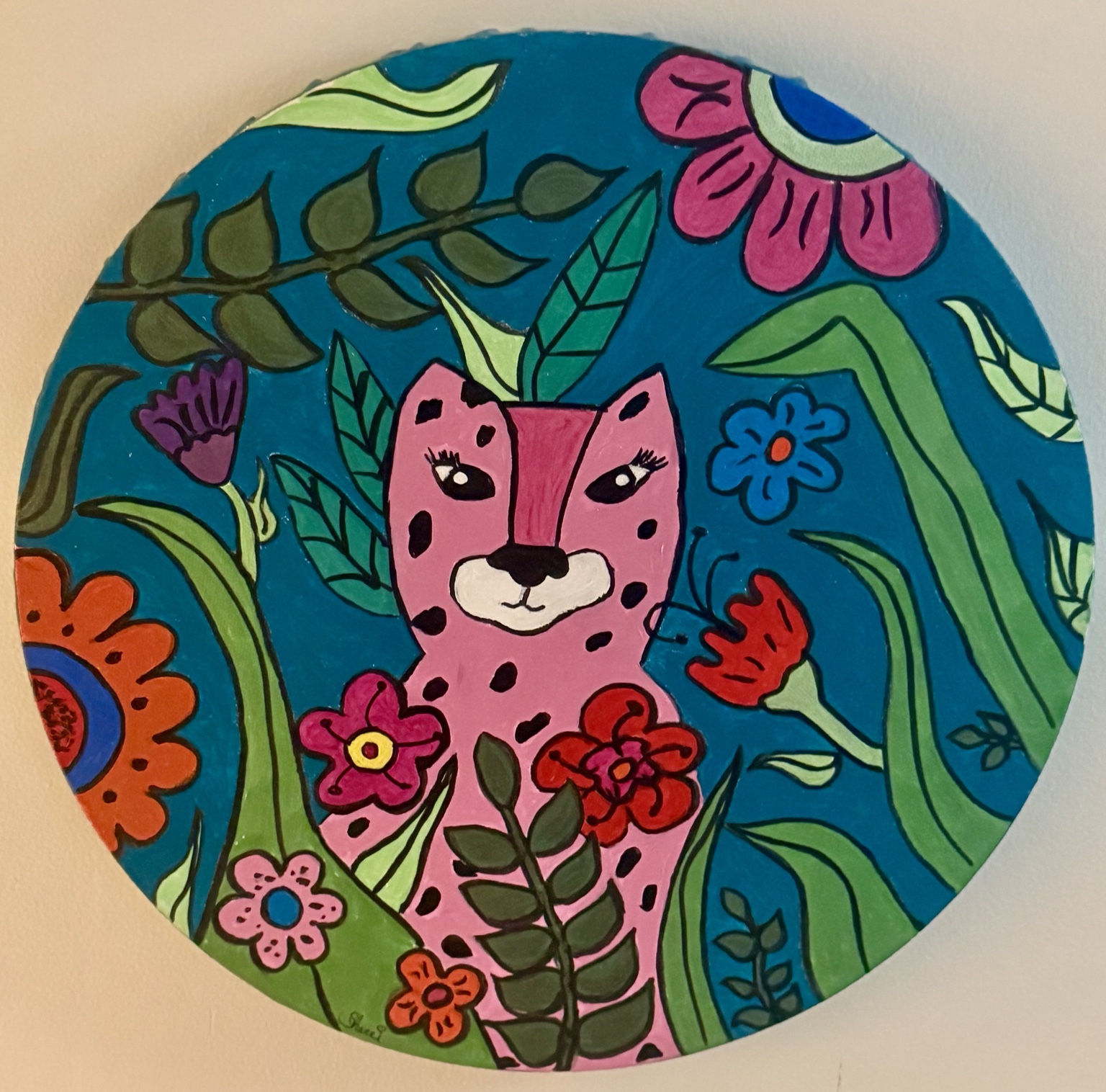 Pink leopard surrounded by bright flowers and green leaves on a round canvas