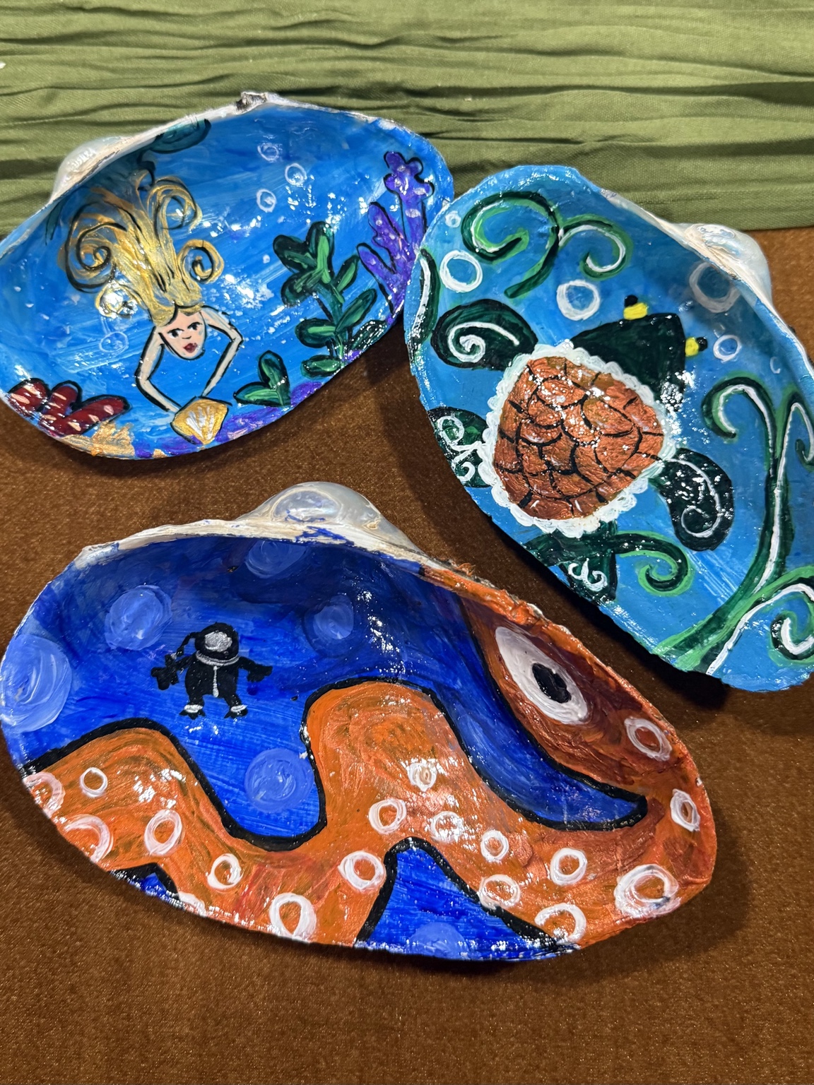 Three painted seashells with a mermaid, turtle, and octopus