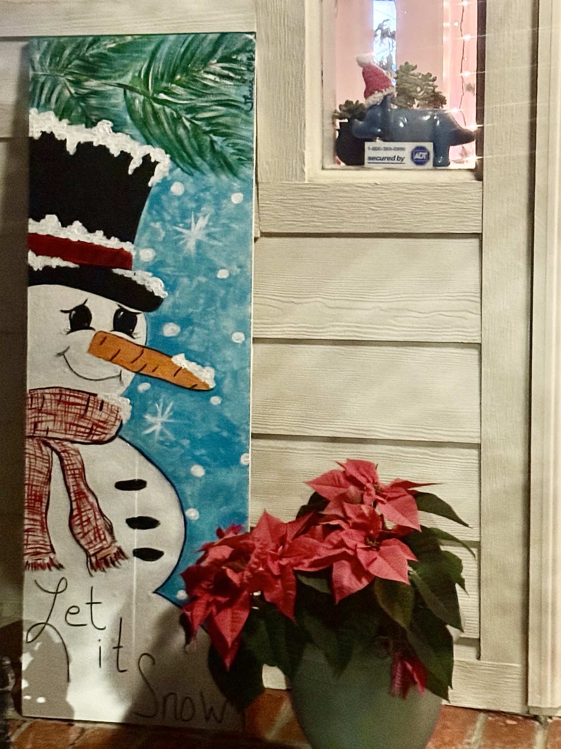 Snowman on a porch beneath Let it snow lettering