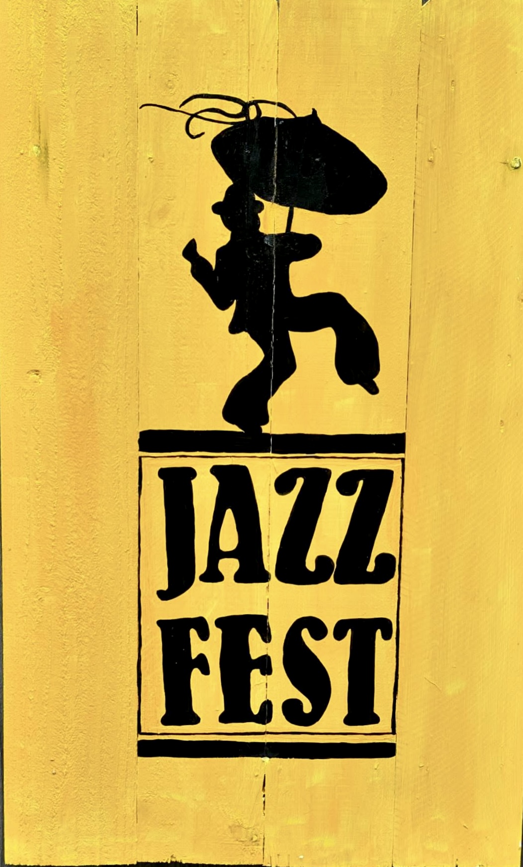 Black silhouette of a musician and Jazz Fest lettering on a yellow background