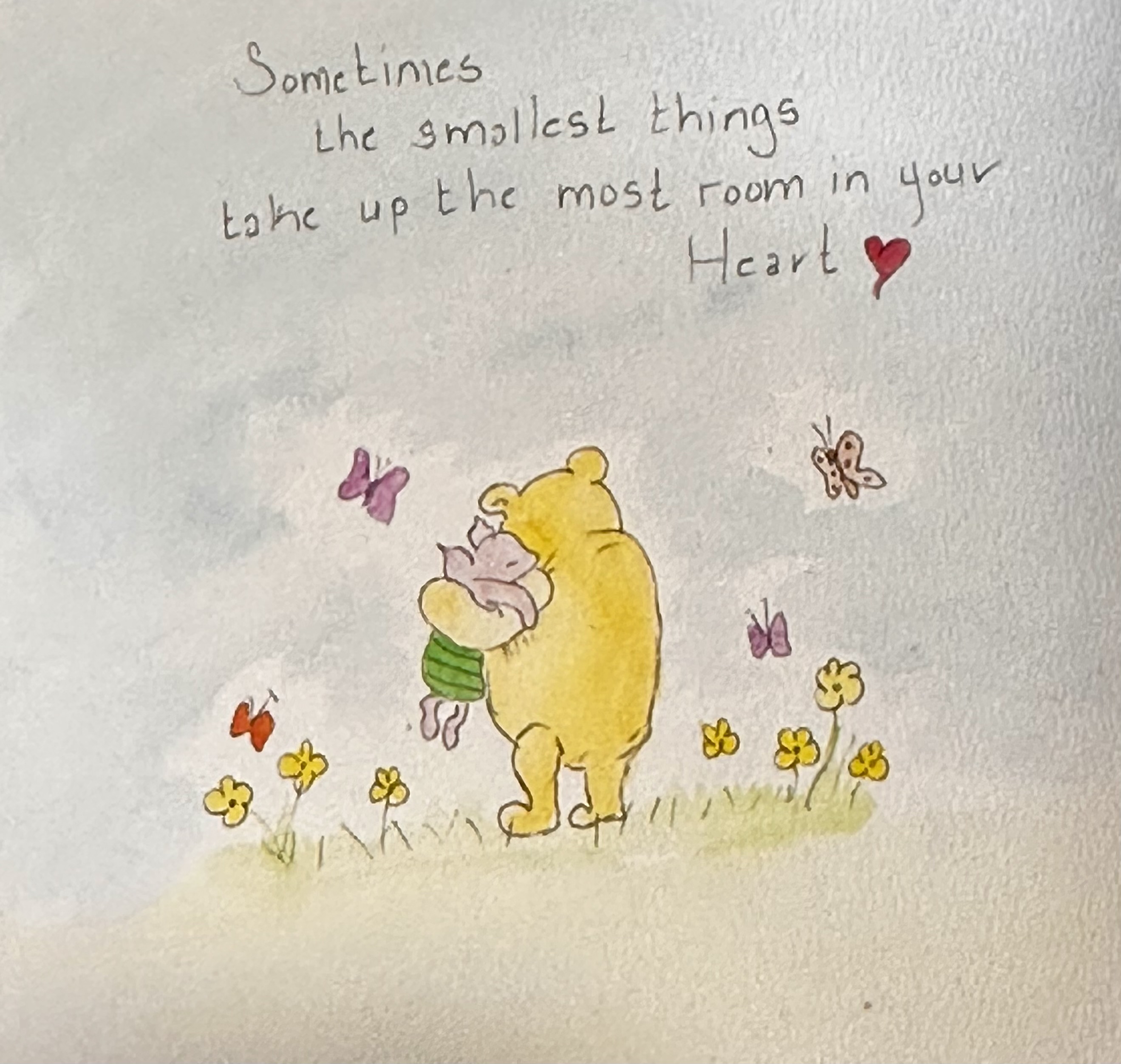 Pooh holding Piglet close in a field of yellow flowers