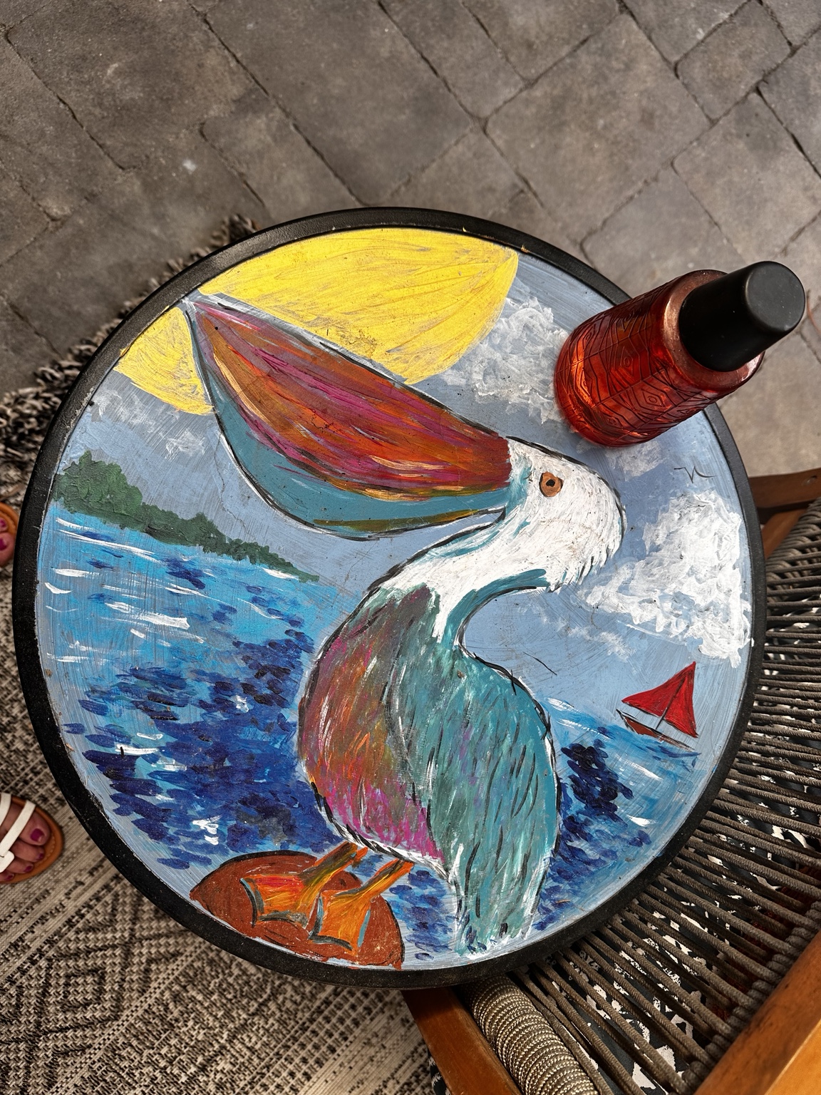 Round painted table with a pelican, bright sun and sailboats