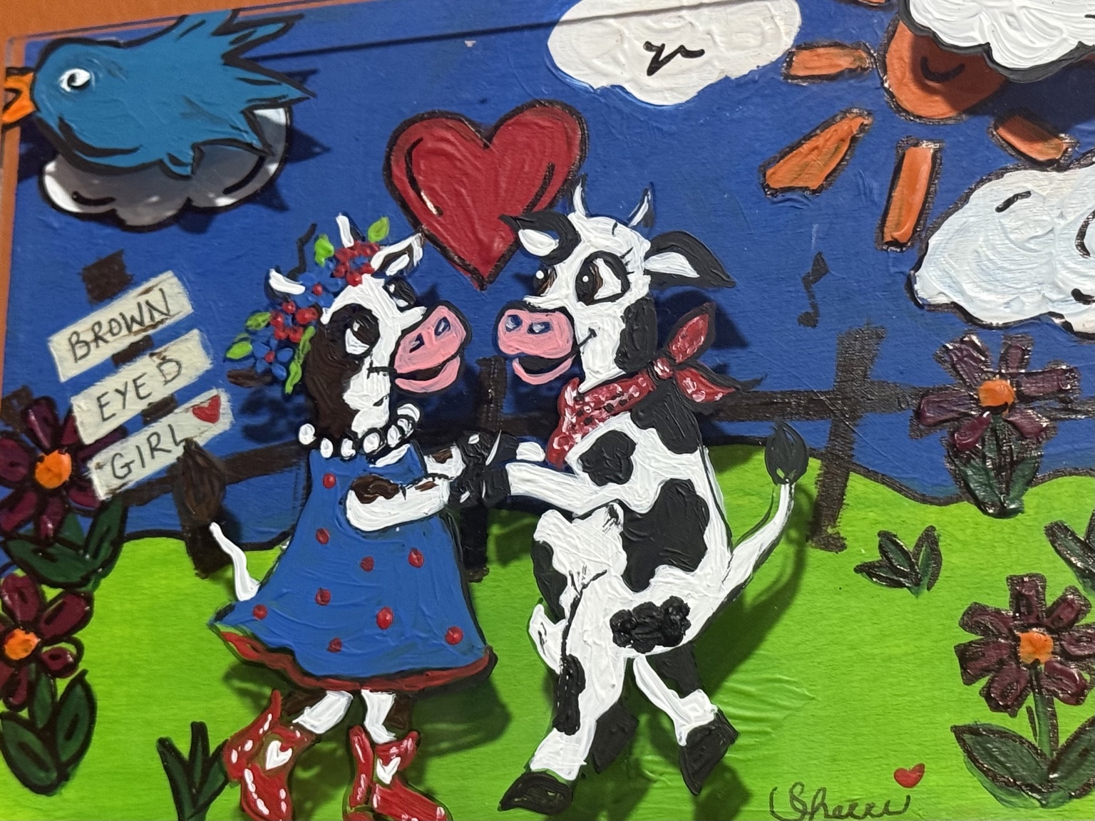 Two black-and-white cows dancing in a field beneath a red heart